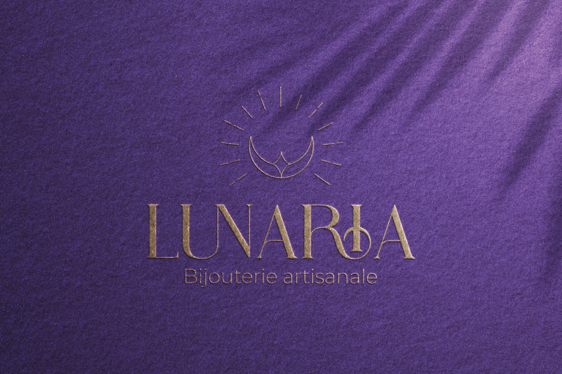 Logo Lunaria en dorure sur une surface violette texturée.